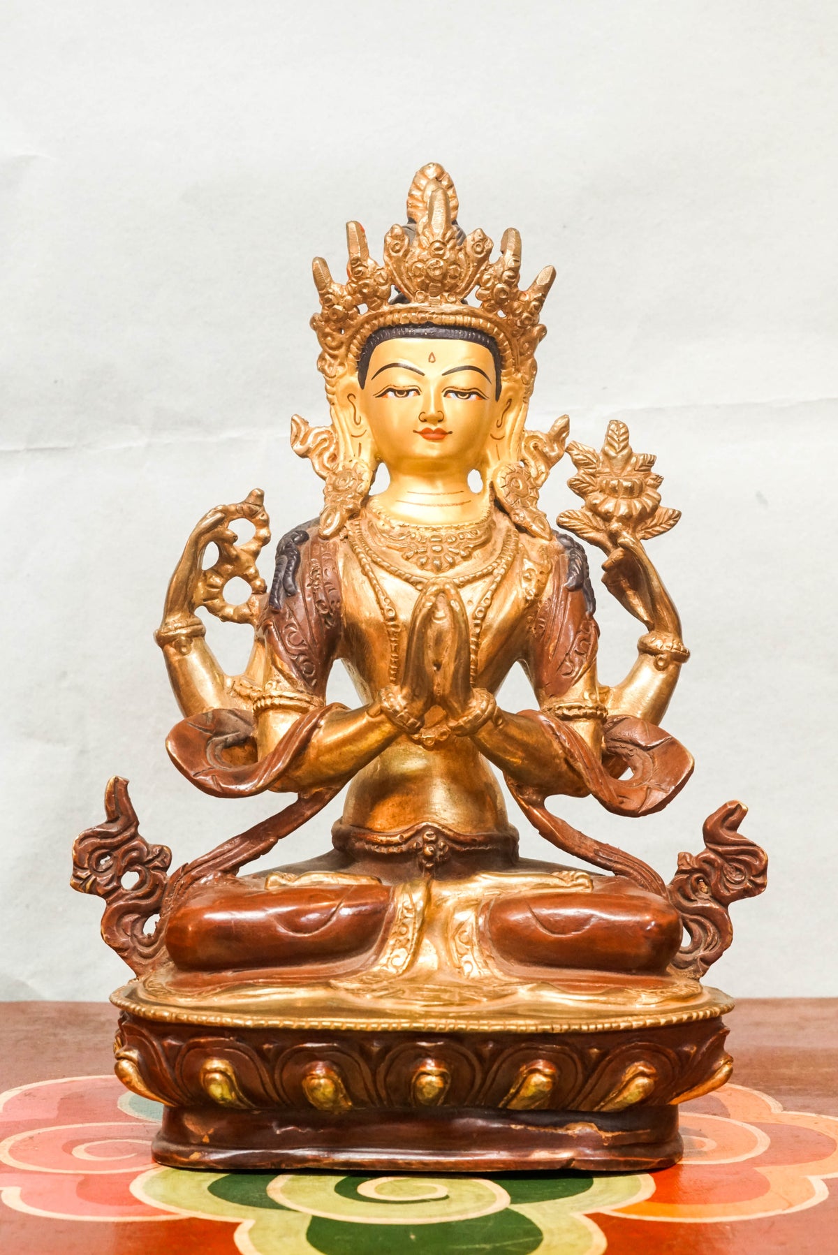 Four-armed Chenrezig (Avalokiteshvara), the Bodhisattva of Compassion, Tibetan Buddhist bronze statue seated in full lotus posture on a lotus pedestal, with two hands joined in prayer (anjali mudra) holding a wish-fulfilling jewel, and two outer hands holding a crystal mala and lotus flower, adorned with a five-leaf crown and bodhisattva ornaments, symbolizing infinite compassion and enlightened activity.