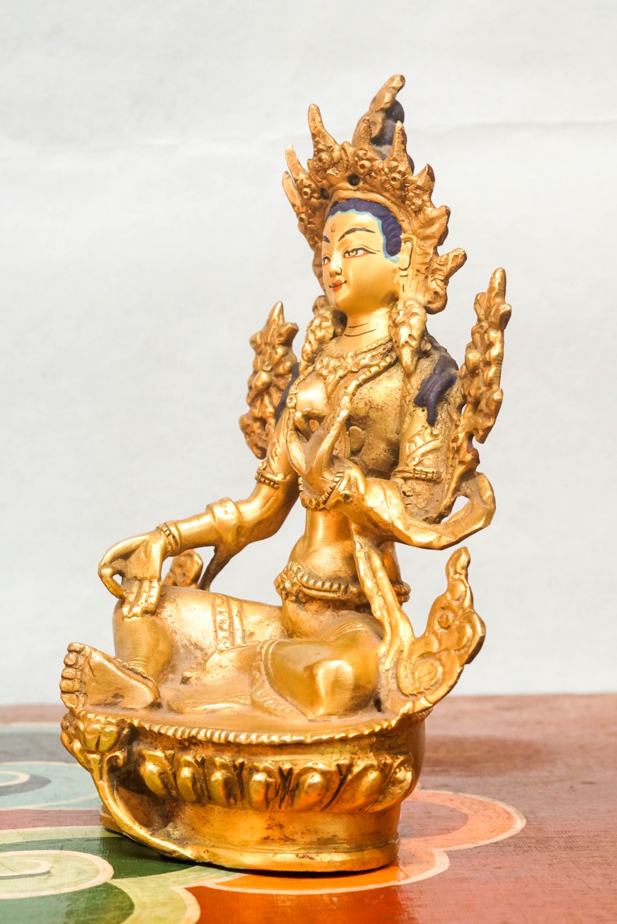 Gold-plated Green Tara (Shyama Tara) statue in Tibetan Buddhist style, seated in royal ease posture on a lotus pedestal, with one leg extended, right hand in generosity mudra and left hand holding a lotus flower, wearing a five-leaf crown and jeweled ornaments, symbolizing swift compassion, protection, and enlightened activity.