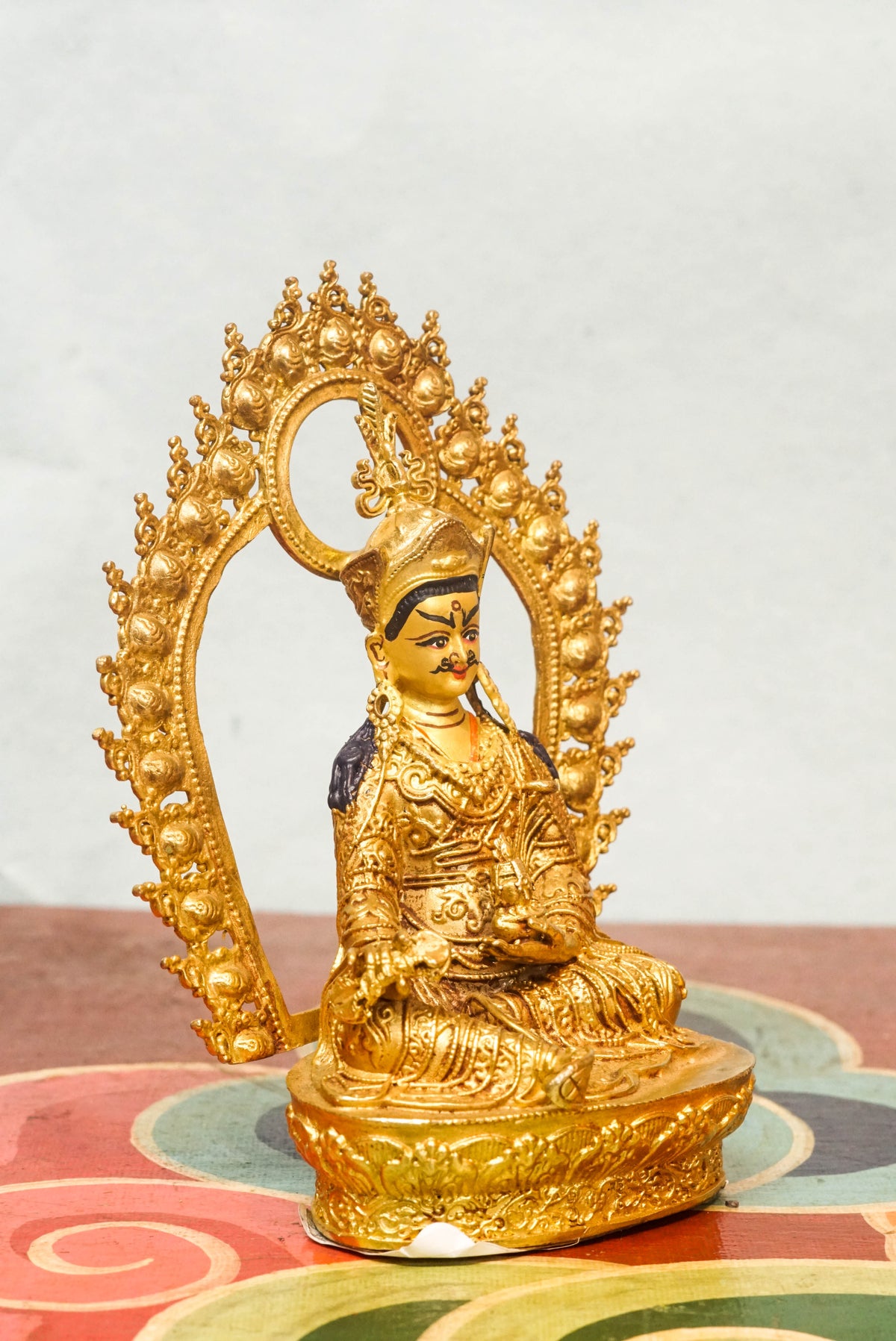 Gilt bronze statue of Guru Rinpoche (Padmasambhava), the Lotus-Born master of Tibetan Buddhism, seated in royal ease posture on a lotus base, wearing a lotus crown and monastic robes, with ornate halo and traditional Himalayan Buddhist craftsmanship.