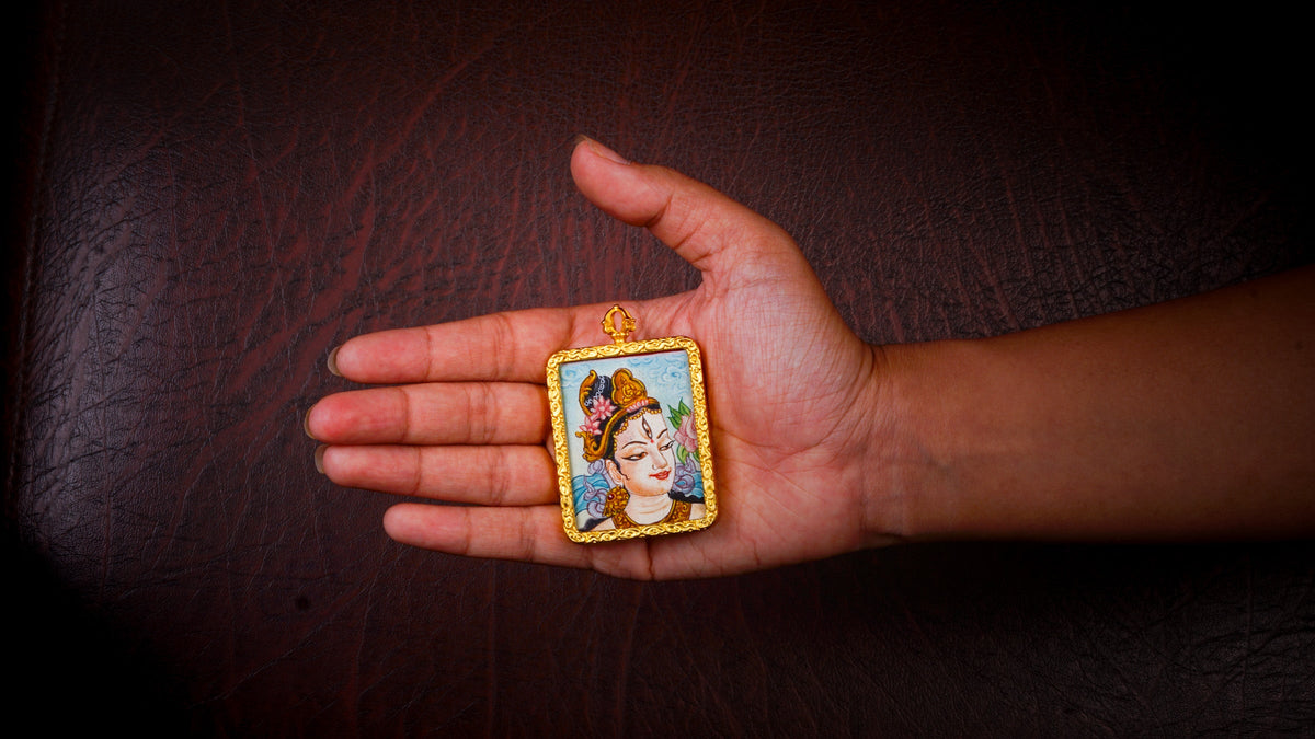 White Tara Ghau pendant featuring a miniature Tibetan Buddhist goddess of compassion artwork in a decorative gold-tone frame handcrafted in Nepal.