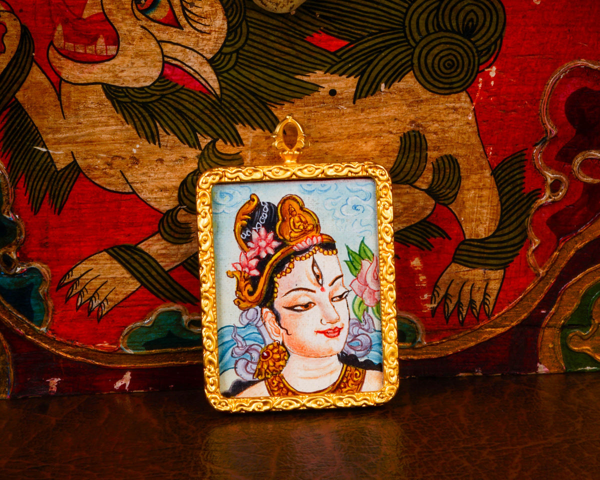 White Tara Ghau pendant featuring a miniature Tibetan Buddhist goddess of compassion artwork in a decorative gold-tone frame handcrafted in Nepal.