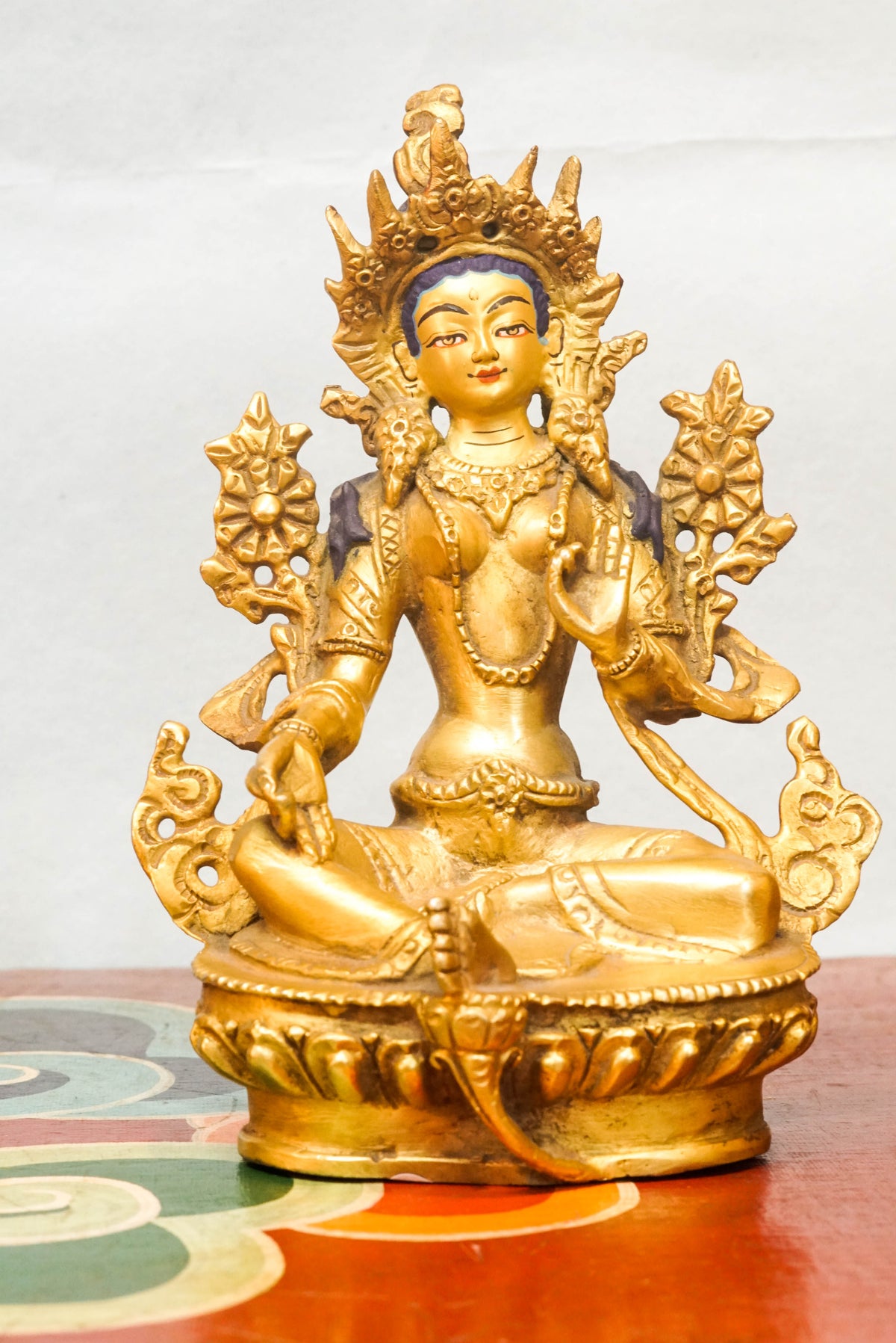 Gold-plated Green Tara (Shyama Tara) statue in Tibetan Buddhist style, seated in royal ease posture on a lotus pedestal, with one leg extended, right hand in generosity mudra and left hand holding a lotus flower, wearing a five-leaf crown and jeweled ornaments, symbolizing swift compassion, protection, and enlightened activity.