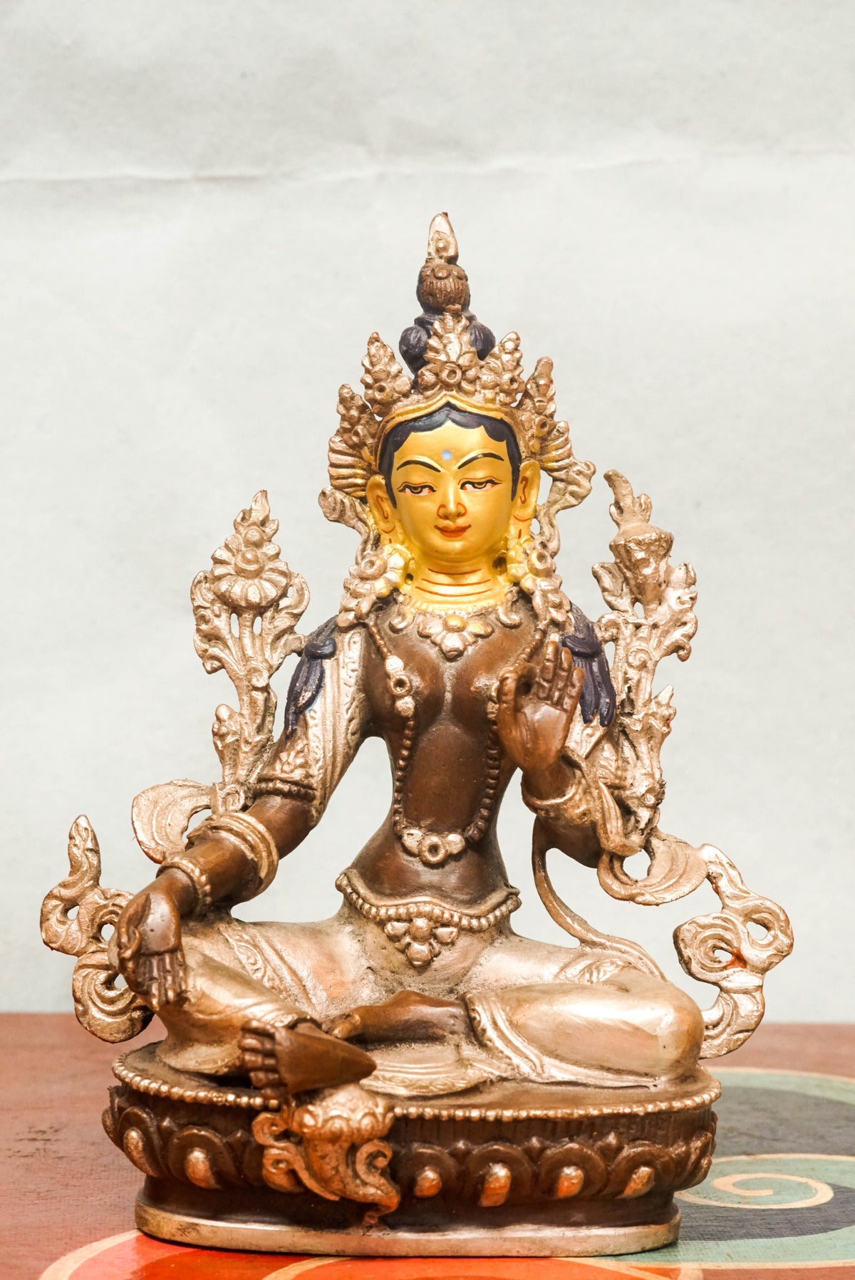 Gilt bronze statue of Green Tara (Shyama Tara), the female Bodhisattva of compassion in Tibetan Buddhism, seated in royal ease posture on a lotus base with her right leg extended, wearing a five-leaf crown and adorned with jewelry, symbolizing swift protection and enlightened activity.
