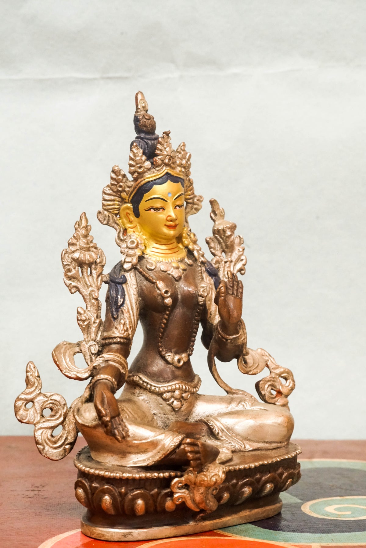 Gilt bronze statue of Green Tara (Shyama Tara), the female Bodhisattva of compassion in Tibetan Buddhism, seated in royal ease posture on a lotus base with her right leg extended, wearing a five-leaf crown and adorned with jewelry, symbolizing swift protection and enlightened activity.