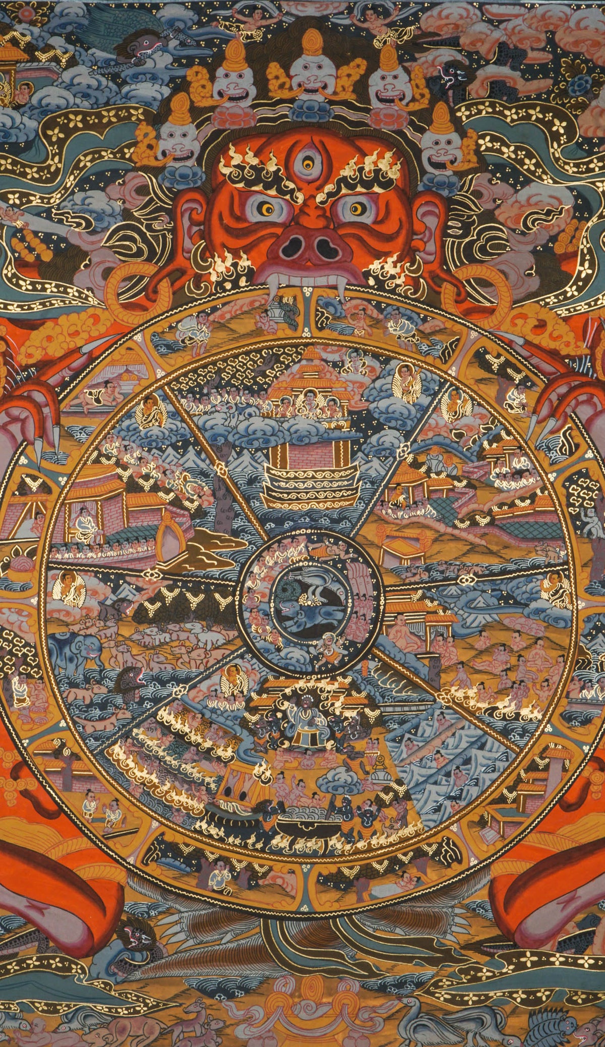 Thangka-style painting featuring a large circular wheel divided into multiple sections filled with small figures, buildings, and landscape scenes, encircled by decorative rings, held by a large red multi-eyed figure with extended arms, surrounded by clouds, flames, and ornate patterns in red, gold, blue, and black tones.