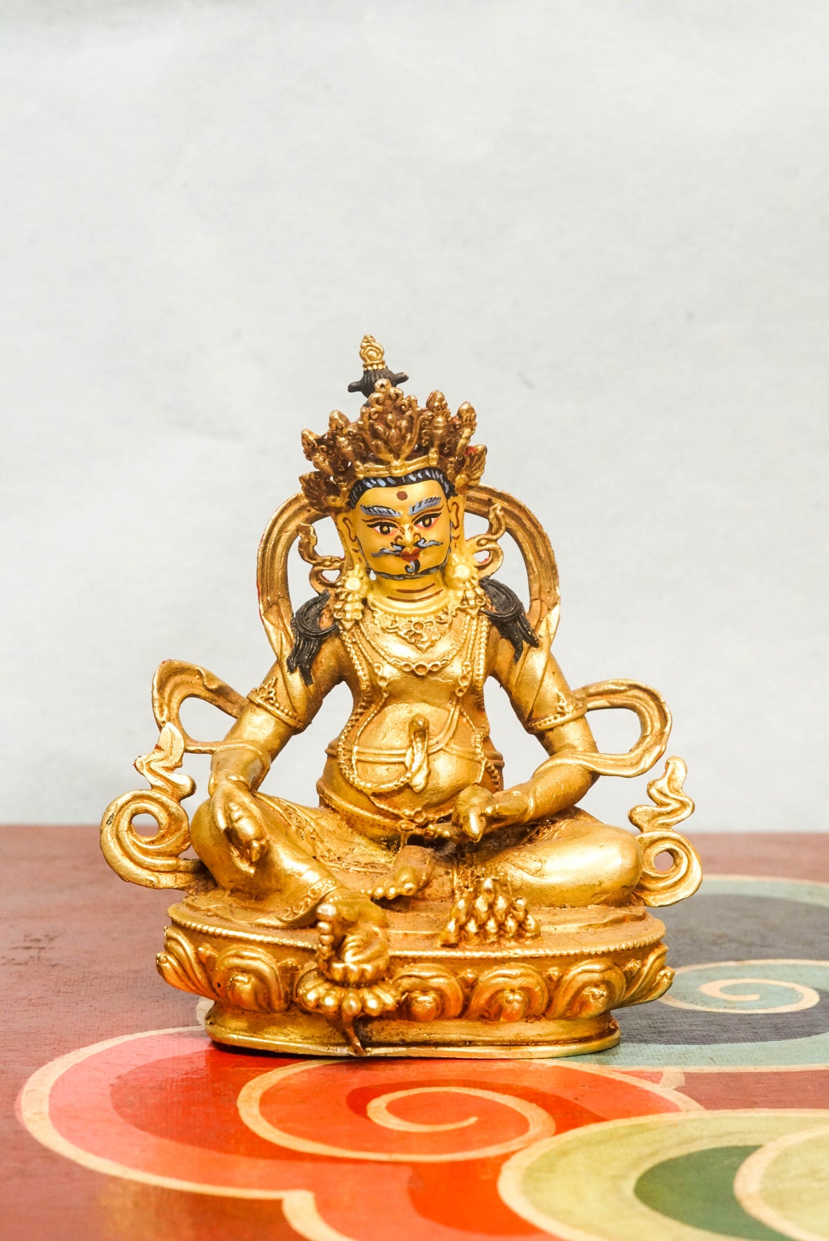 Handmade gold Zambala statue adorned with crown and jewelry, symbolizing prosperity and removal of obstacles.